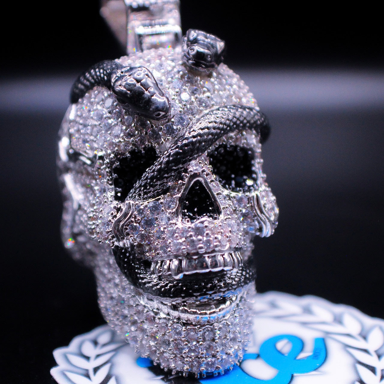 3d silver skull covered in diamonds with snake wrapped around displayed on black display 