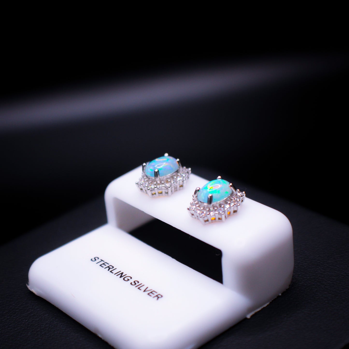 Johnny's Ice & Co JI-1194 Opal Earrings featuring sparkling opal stones and silver hooks, displayed on a neutral background.