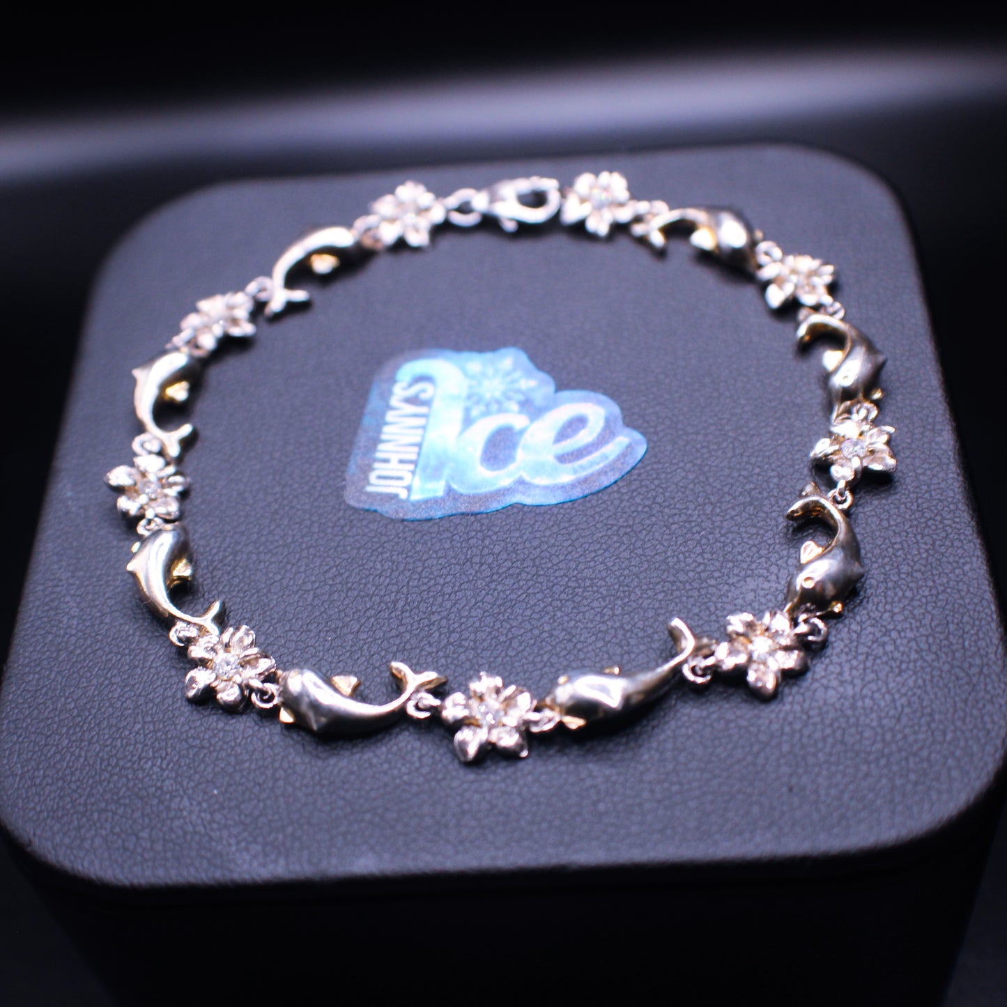 Silver .925 dolphin and petal design bracelet by Cash In, showcasing intricate dolphin and floral motifs on a stylish bracelet.