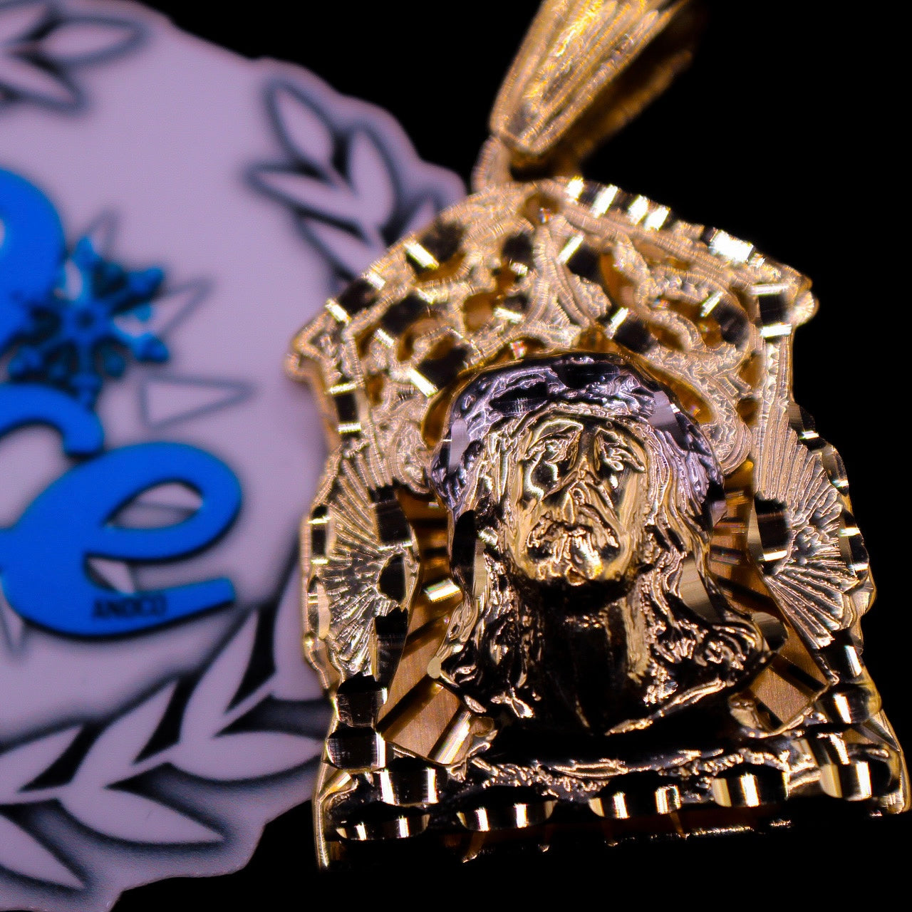 A gold pendant featuring a red ruby piece with intricate engravings, displayed against a branded background.
