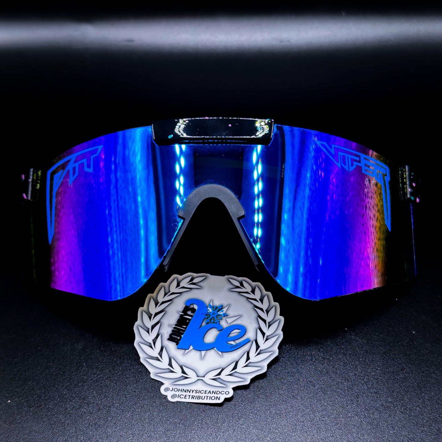 A pair of sunglasses with reflective blue/purple lenses, positioned above a logo with the text 'Ice'.