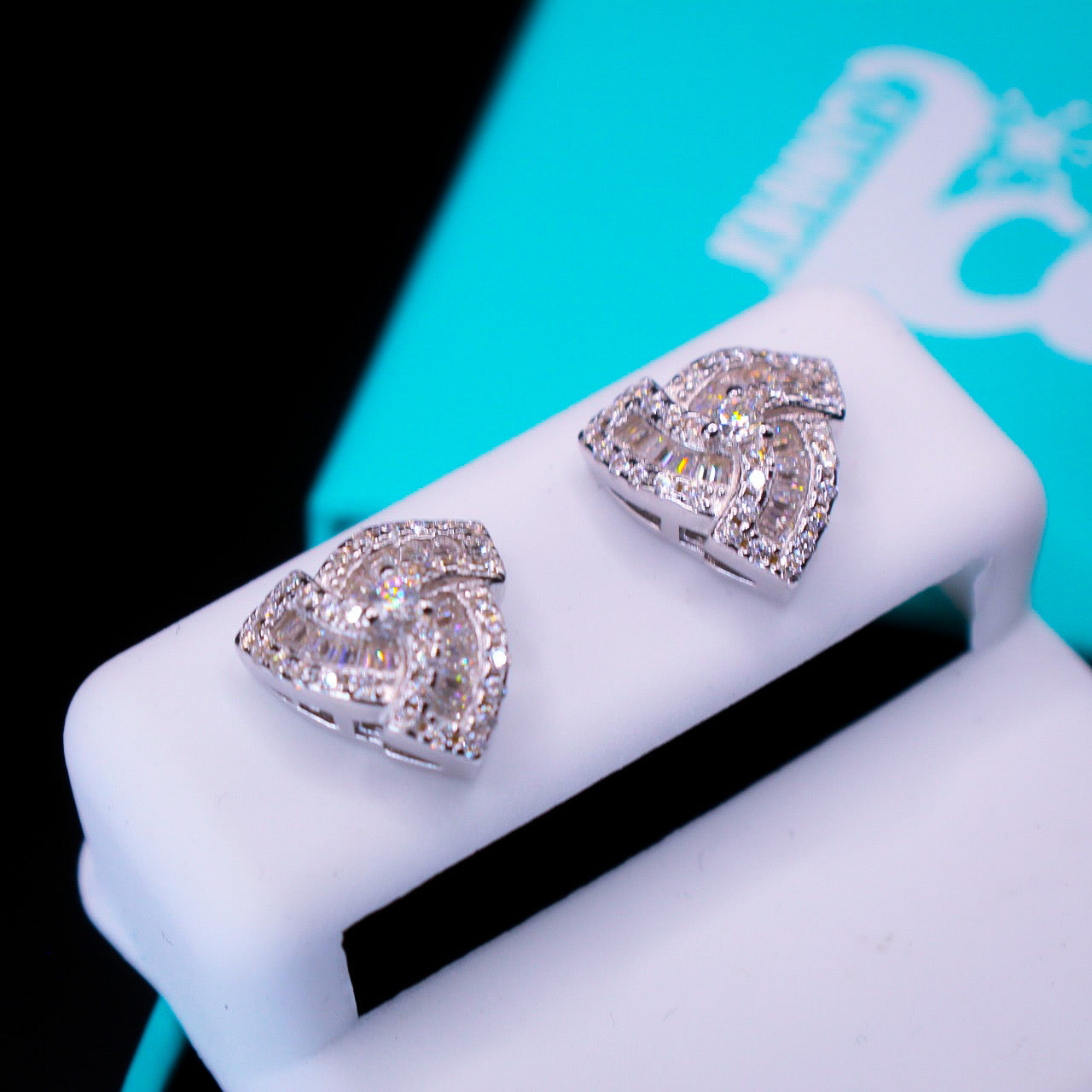 triangular shaped diamond earrings on a white stand with a blurred background