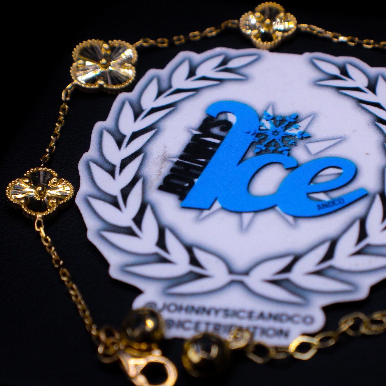 Gold bracelet with a decorative charms featuring the 'Ice' logo on a black background