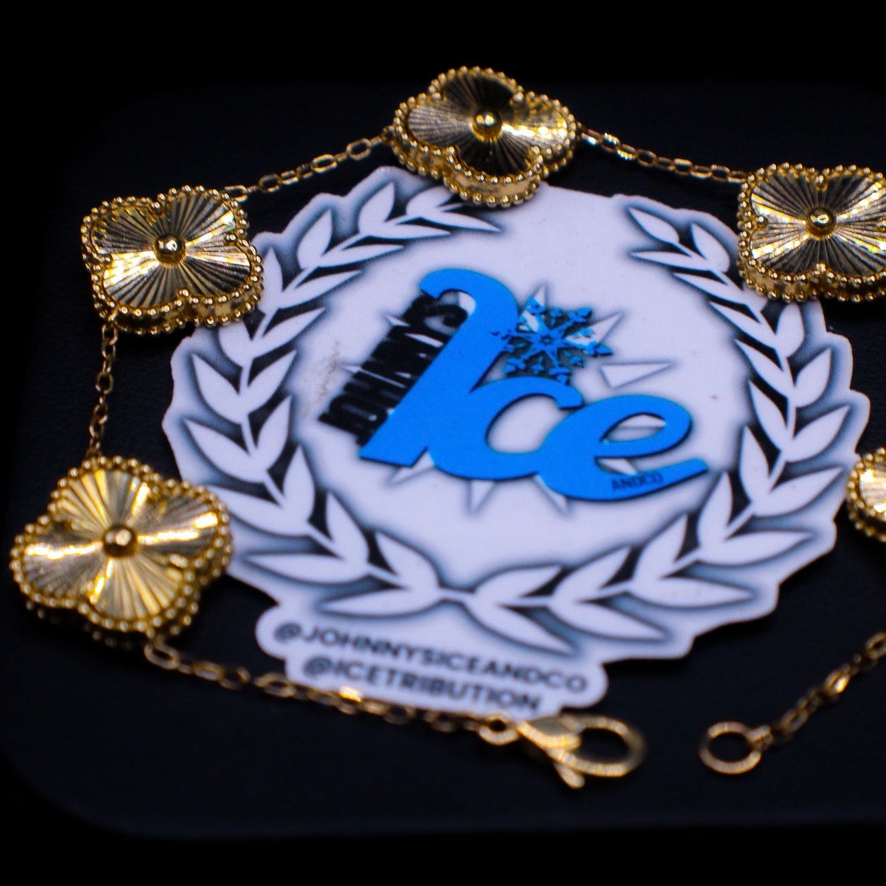 Decorative bracelet with gold charms and 'Ice' logo on a black background