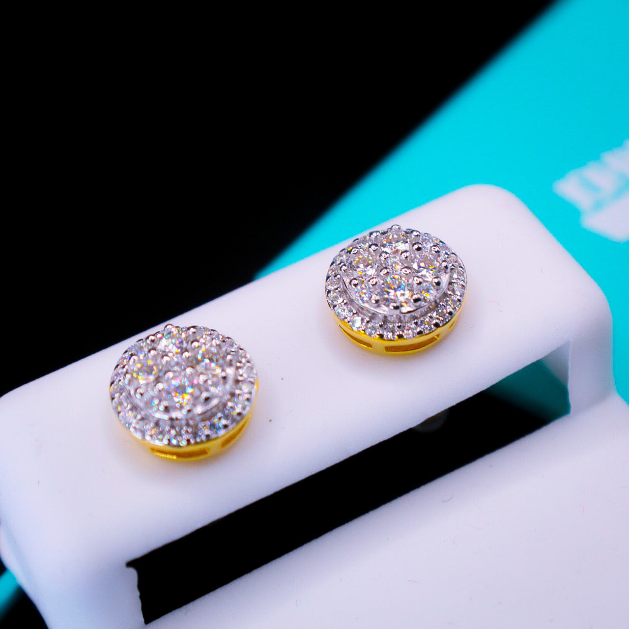 Pair of sparkling silver earrings on a white stand with a black and blue background