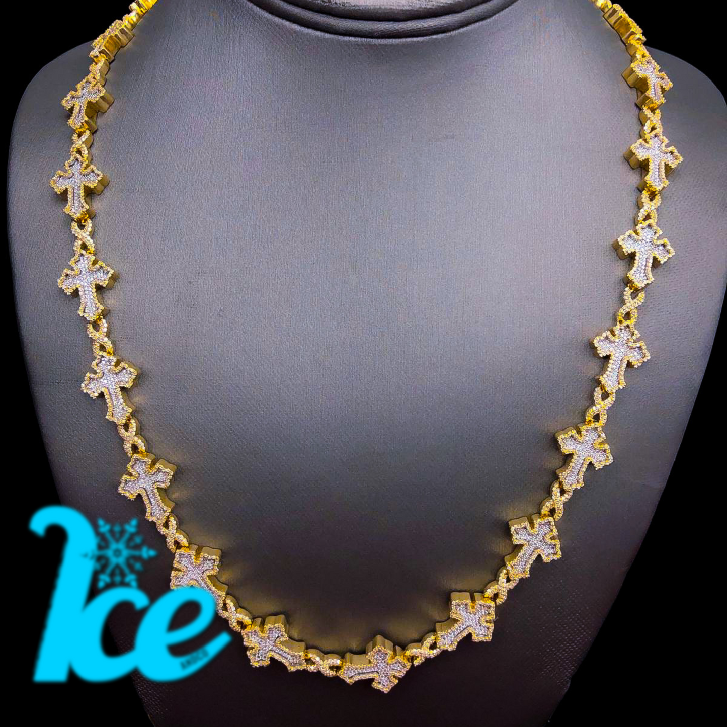 A gold necklace with cross-shaped pendants, displayed on a mannequin bust.