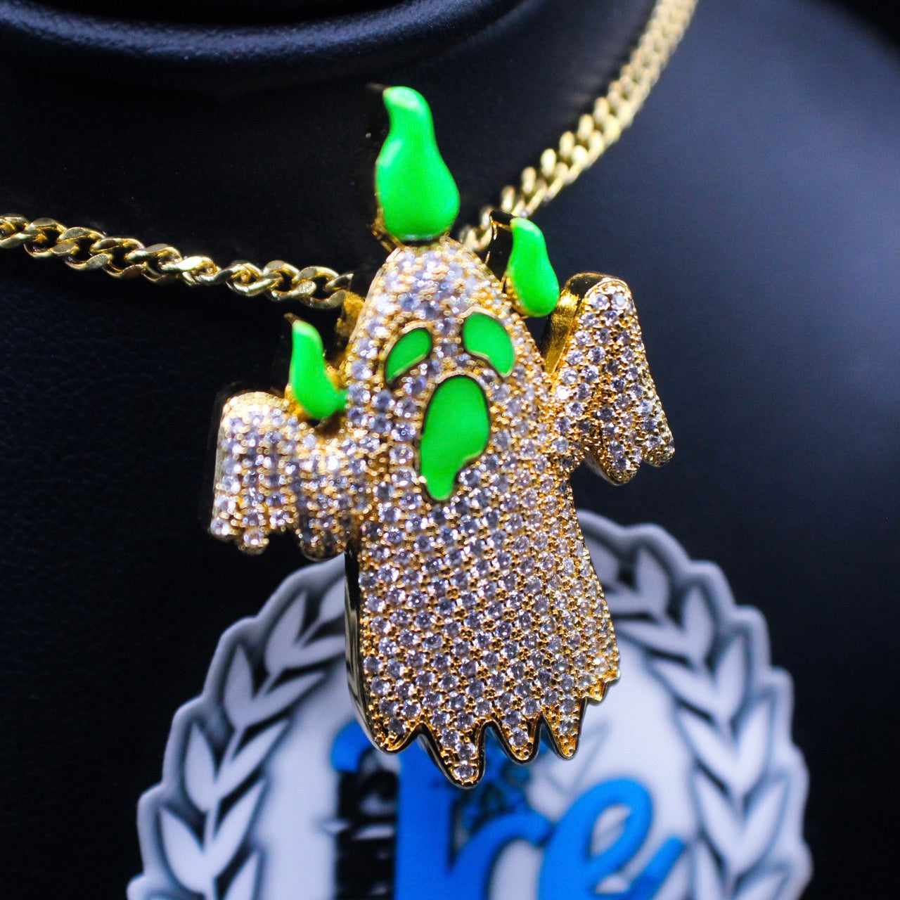 A silver-colored necklace featuring a 3D enamel-coated ghost-shaped charm with green accents and a hook bail.