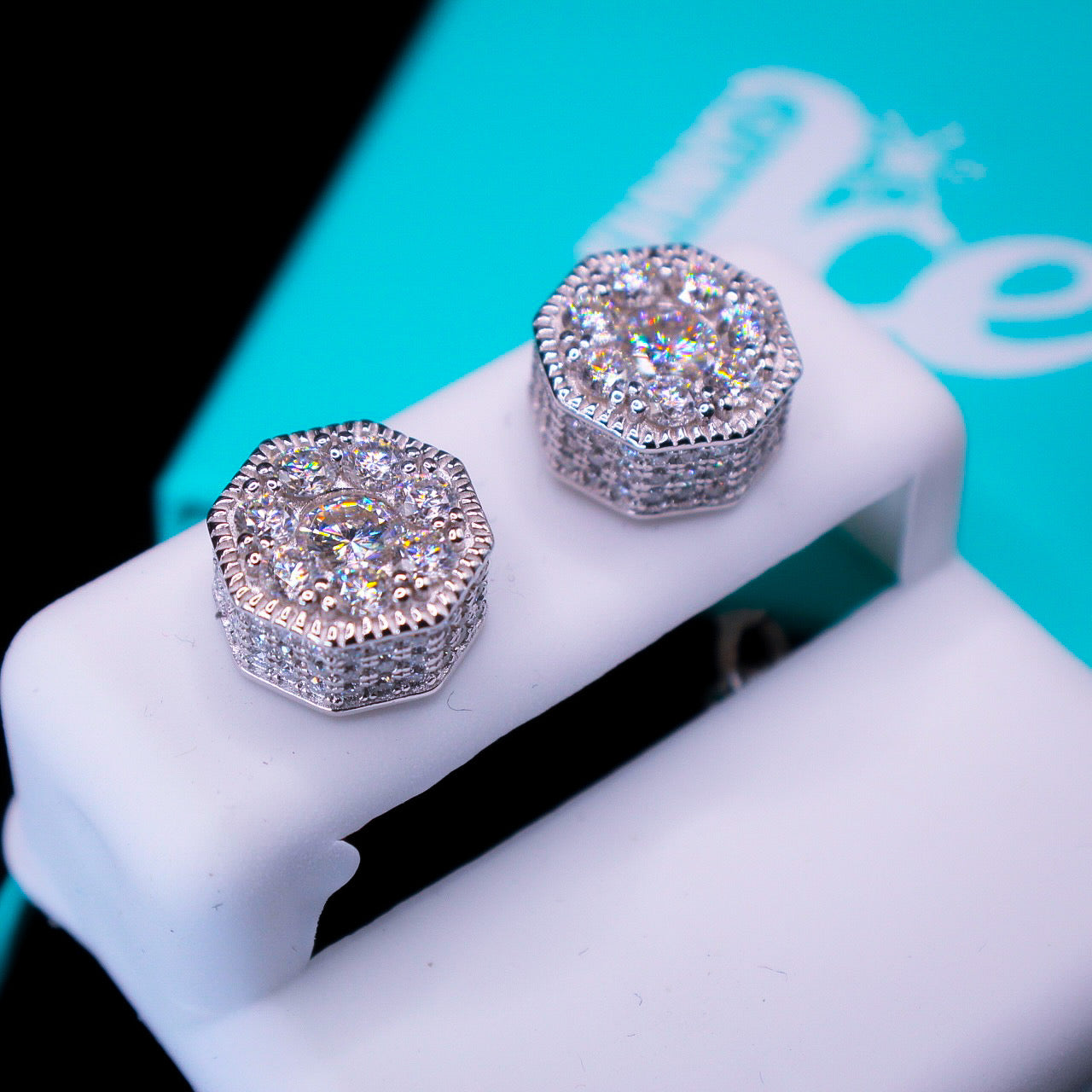 Pair of diamond earrings on a white stand with a blurred background
