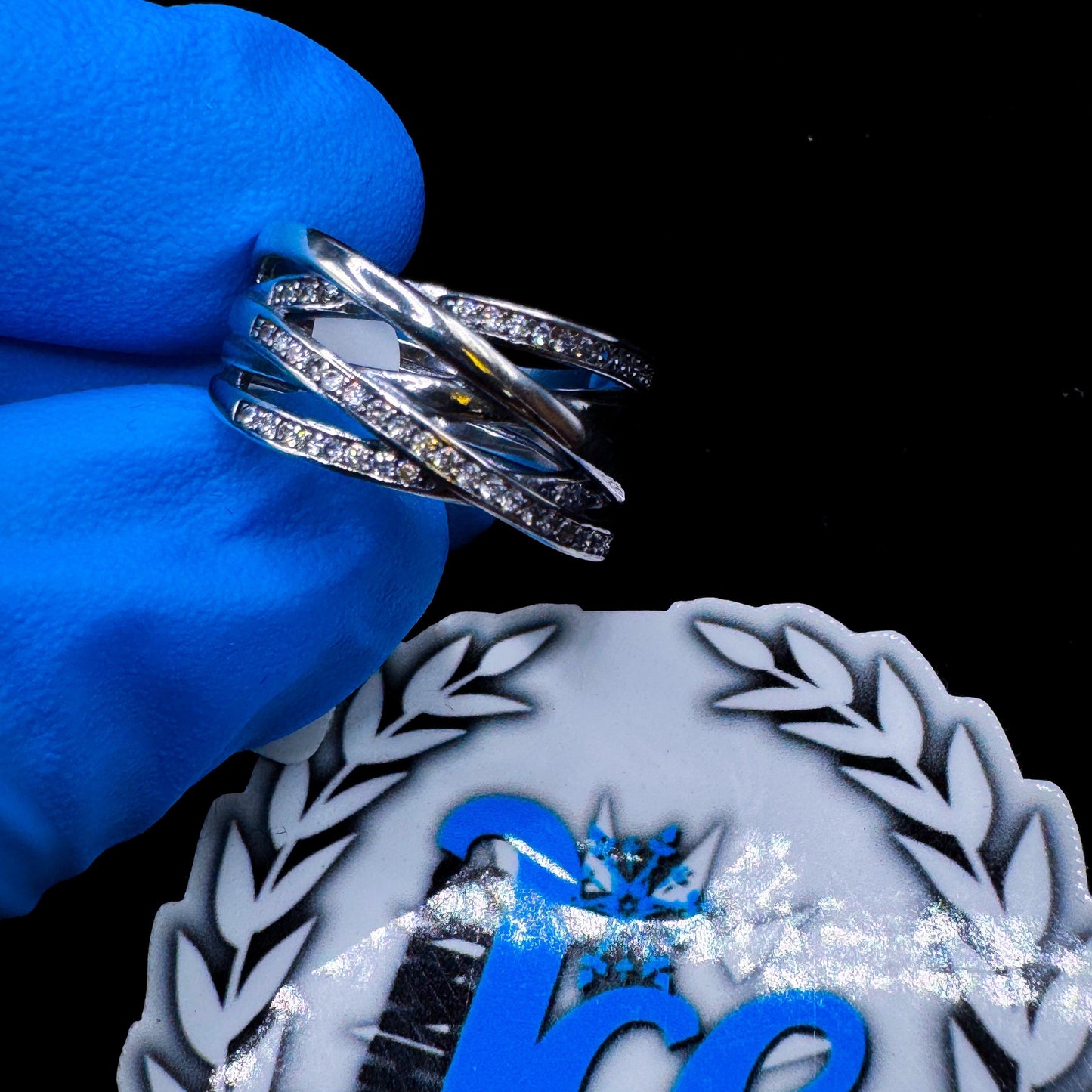 A silver ring with multiple bands and embedded stones, displayed on a blue cushion.