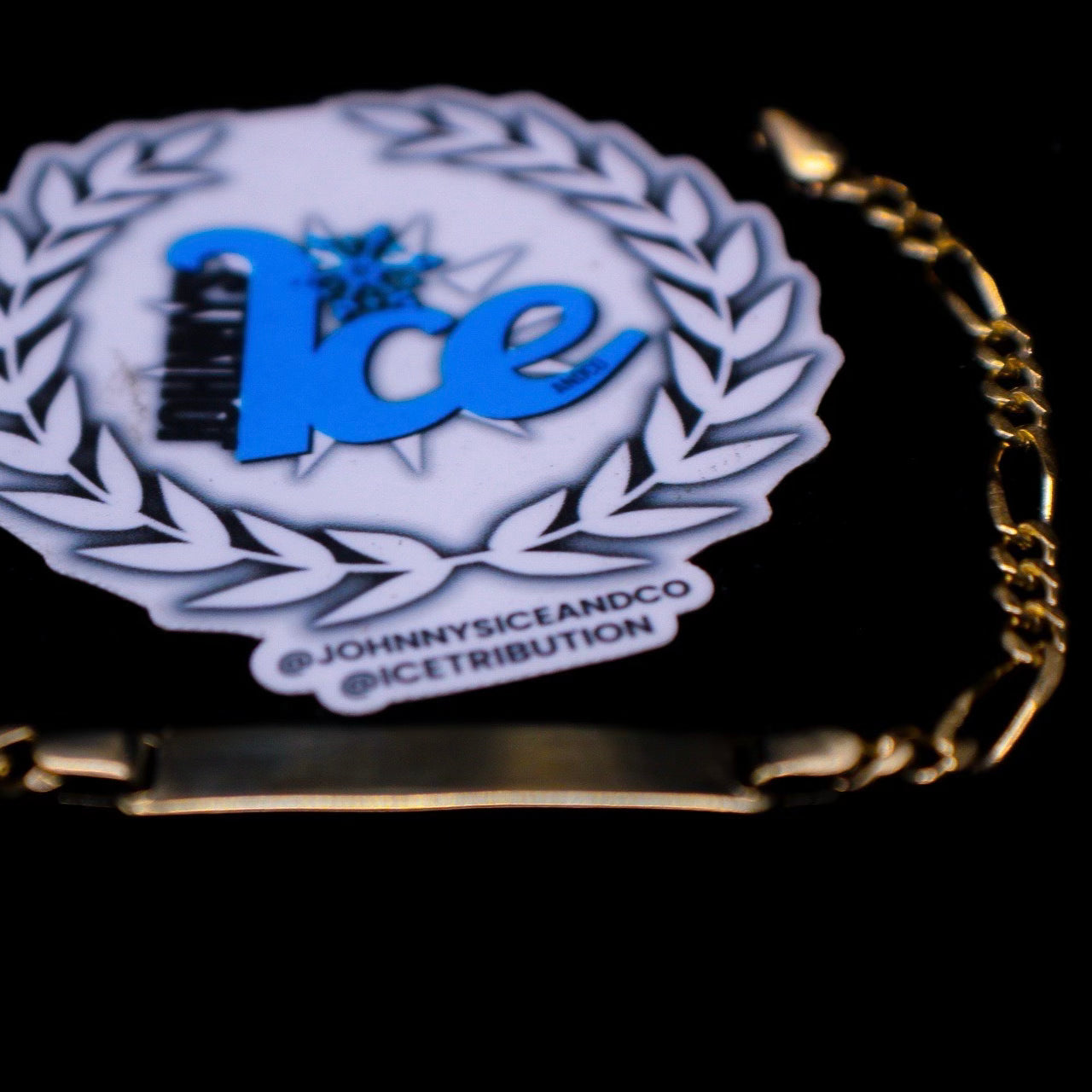 Gold bracelet with a 'Ice' branded pendant on a black background