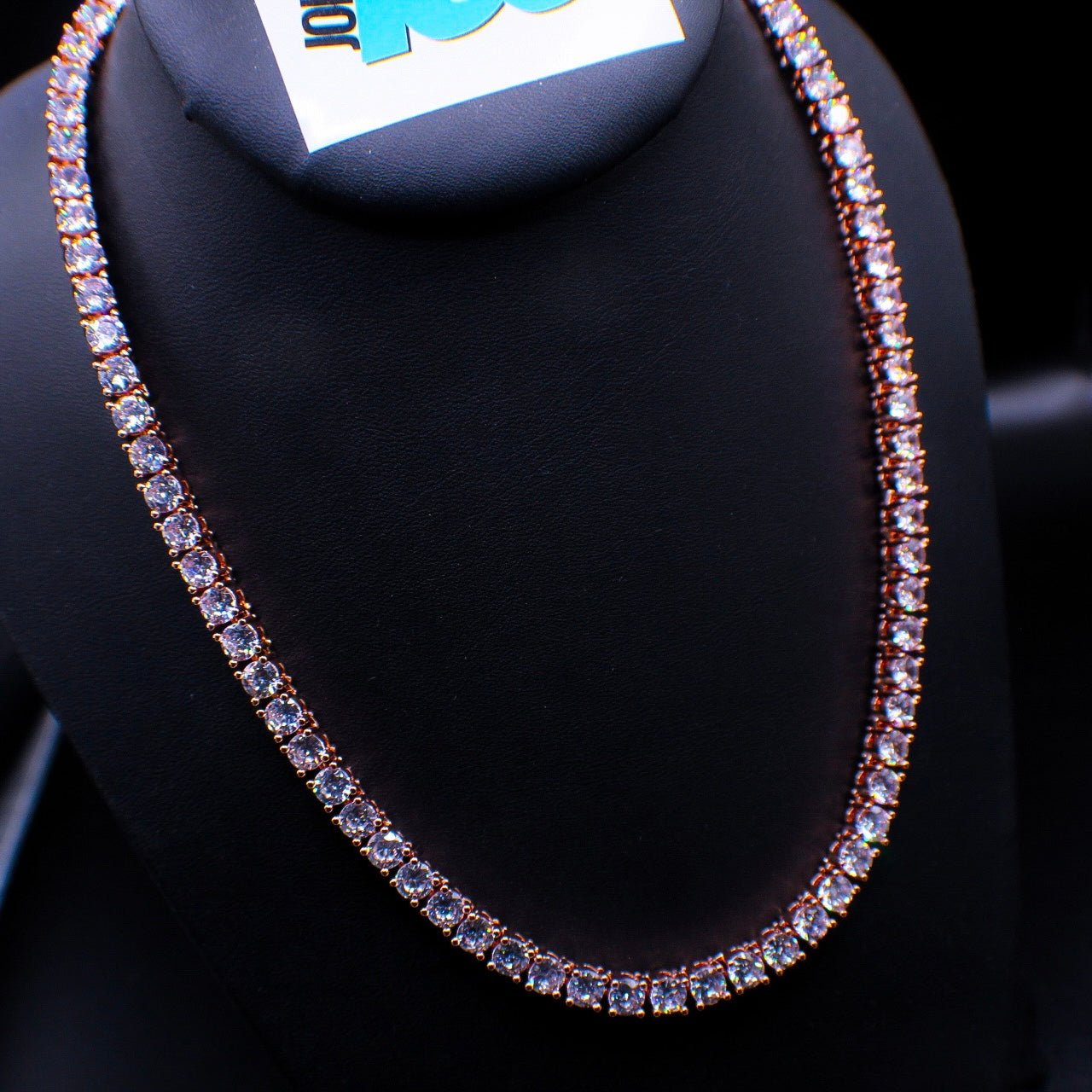 A tennis necklace with silver metal and rose gold finish, featuring multiple solitaire stones.