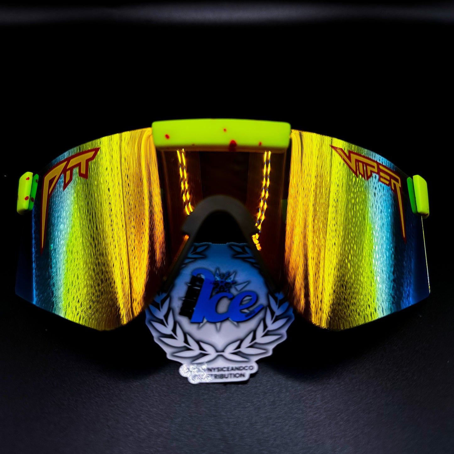 A pair of sunglasses with yellow and orange lenses, featuring blue and green accents, and a reflective surface. The brand logo for Ice is visible on the front.
