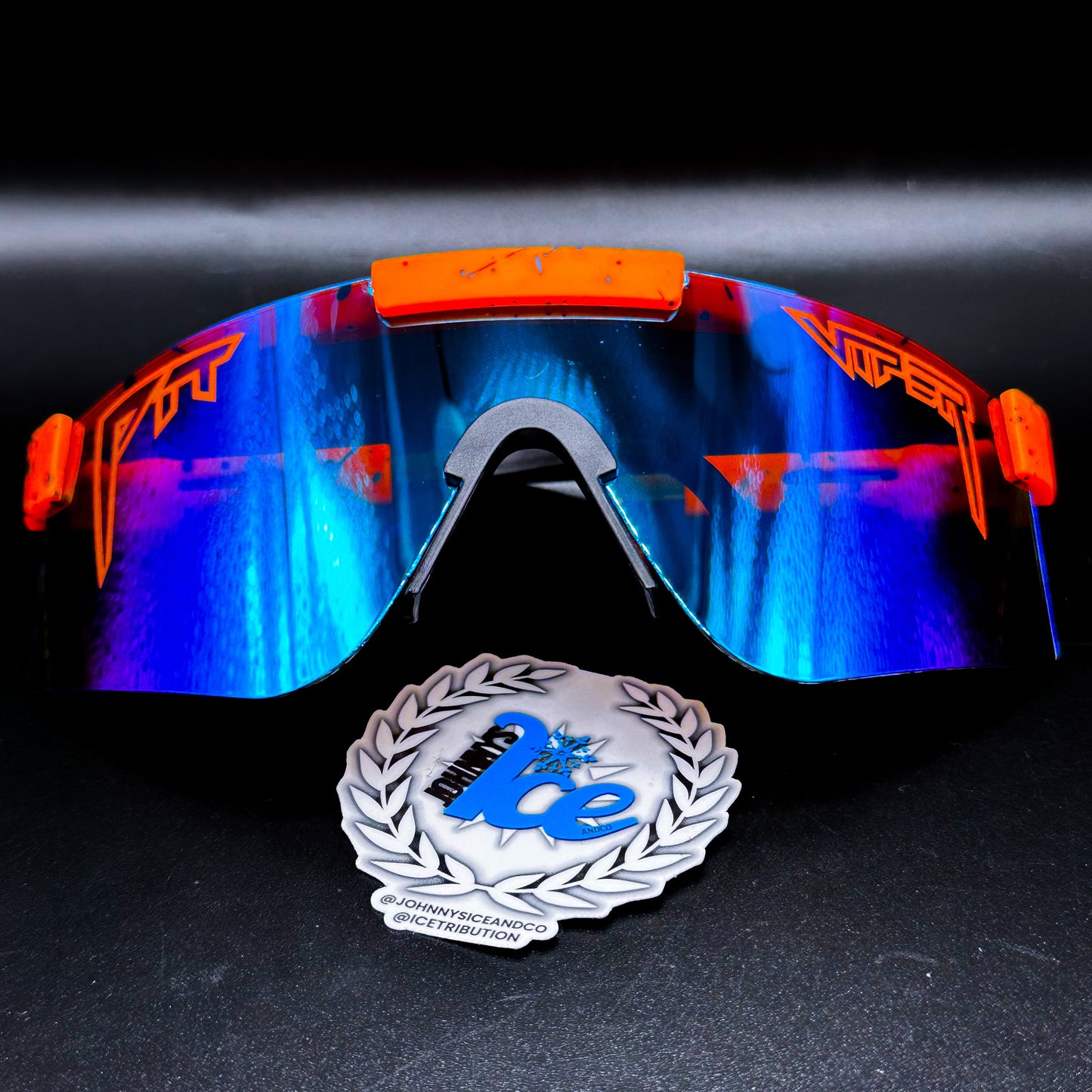 A pair of orange sports sunglasses with blue mirrored lenses, displayed alongside a johnnyice logo