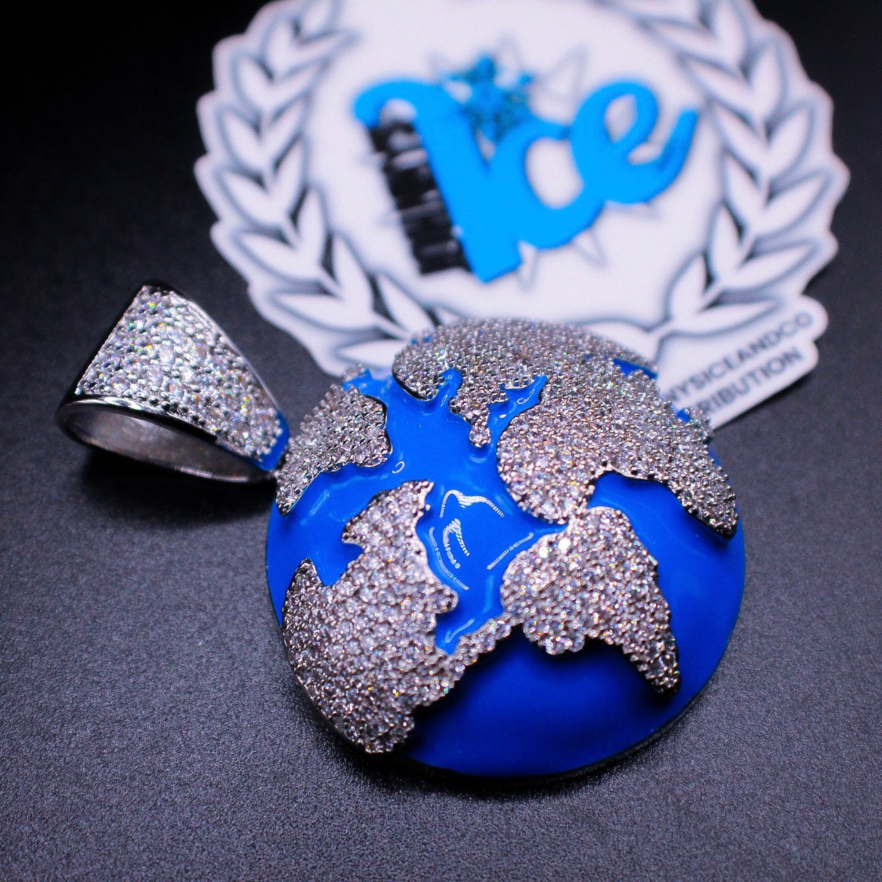 A silver-colored ring with a 3D enamel world map background and multiple sparkling stones on the map.